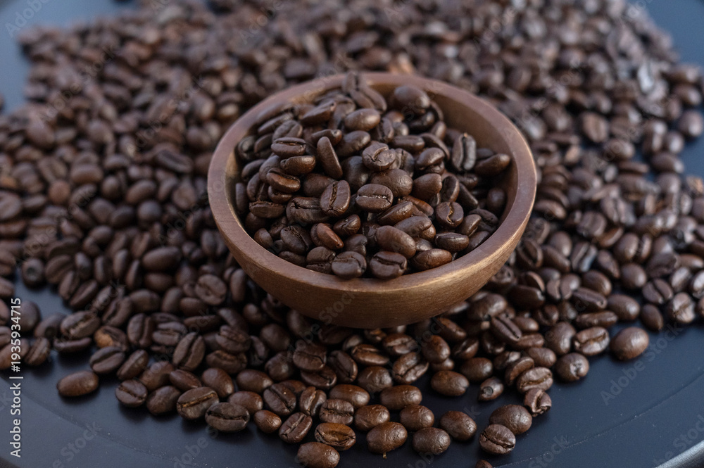 Fototapeta premium Artisan roasted coffee beans in a wooden bowl on a dark textured background