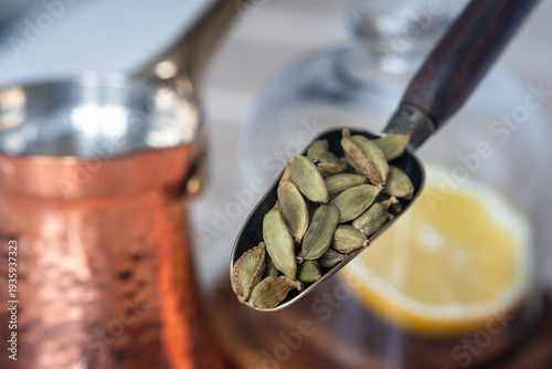 Green cardamom pods in a spoon.