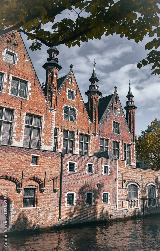 Obraz premium Scenic canals and historic medieval architecture in Bruges, Belgium, featuring traditional Flemish buildings along the water in the iconic European city.