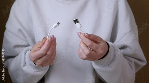 Woman holding broken usb type-c cable. Woman's hands holding the two ends of a broken or cut white usb charging cable, demonstrating the concept of damaged technology, connectivity issues