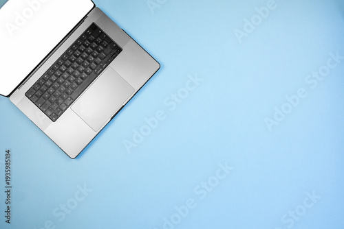 partial silver laptop placed on blue background with large copy area, webinar and virtual meeting concept for online education and remote conferencing by instructor preparing session