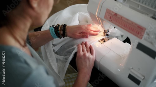 Female dressmaker hands works at a sewing machine with curtains fabrics. Sewing fabric for clothing at work home