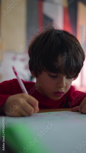 Young boy concentrating while writing on paper at home table, focused childhood learning moment, homework activity and quiet indoor study time