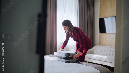 Woman tourist taking clothes from suitcase on bed. Businesswoman unpacking