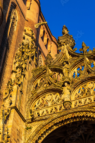 Carved detail of the stone canopy above the entrance of Sainte-Cécile Cathedral illuminated by sunset