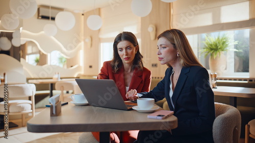 Business partners looking laptop at work meeting in modern restaurant closeup.