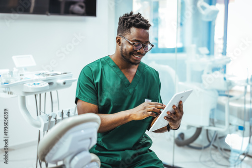 Photos Smiling Dental Professional In Green Scrubs Using Tablet In Modern Dental Clinic
