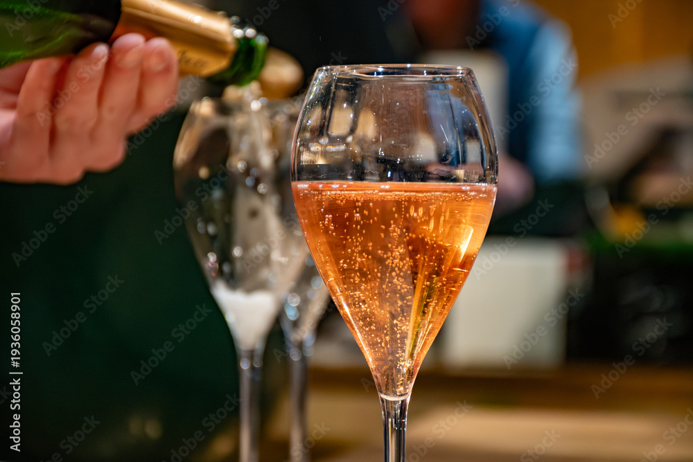 Obraz premium Pouring in glasses of french sparkling wine champagne with little bubbles, tasting wine, celebration, wedding or champagne tour with visit of caves, Reims, France