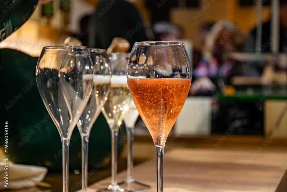 Fototapeta premium Pouring in glasses of french sparkling wine champagne with little bubbles, tasting wine, celebration, wedding or champagne tour with visit of caves, Reims, France