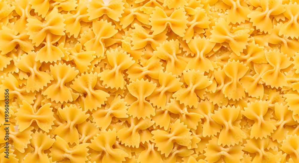 Obraz premium Dense arrangement of farfalle pasta forming a textured background, showcasing the intricate shapes and golden hues of this classic Italian staple, ideal for food-related designs.
