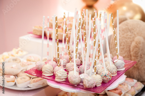 Elegant pink sweet table setup for a birthday celebration featuring beautifully decorated cake pops and delicate desserts in soft pastel tones. 