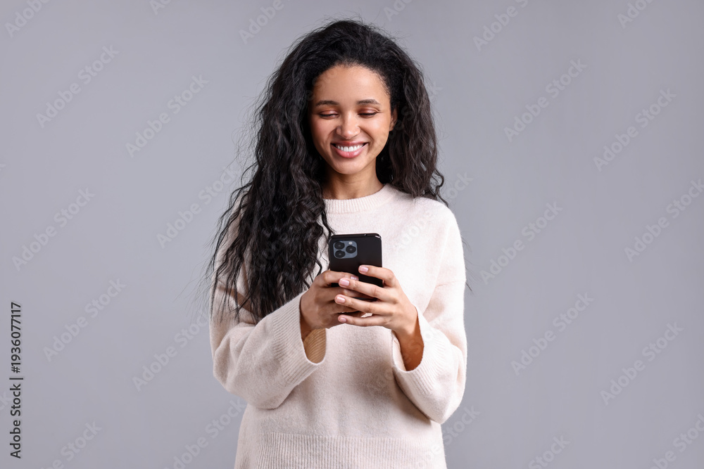 Fototapeta premium Beautiful young woman with smartphone on light grey background