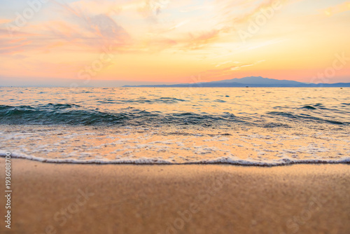 The ocean is calm and the sky is a beautiful orange color