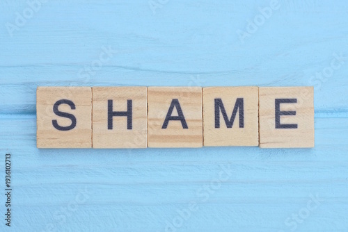 Foto word shame made from wooden gray letters lies on a blue background