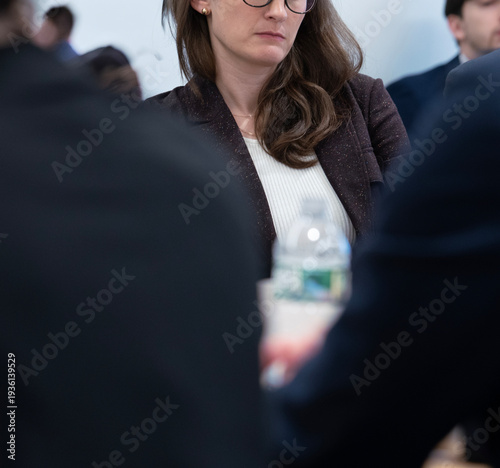 Foto A candid shot captures a professional woman with a serious expression, listening attentively during a corporate meeting or conference