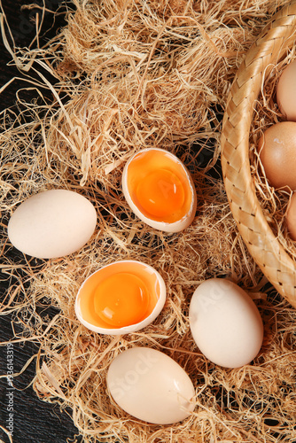 Fresh Free Range Farm Eggs with Orange Yolks in Rustic Wicker Basket on Straw Nest
