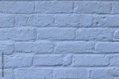 A close-up of an old exterior wall of a building with bricks. Construction material with blue bricks. Background or backdrop with white and blue colors. Painting on exterior bricks.
