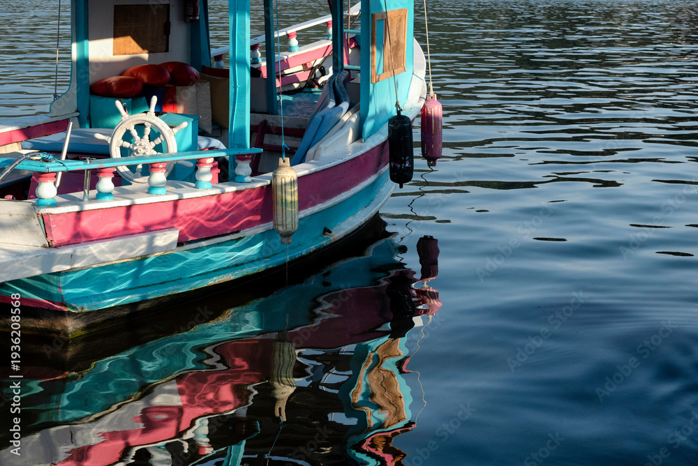 Obraz premium Pink and blue boat and its reflection on the sea