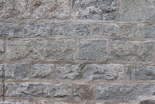 Ancient stone wall texture with large grey stones and cement. Construction industry and old wall repair. Abstract background with rocks on a exterior wall. Gray background.
