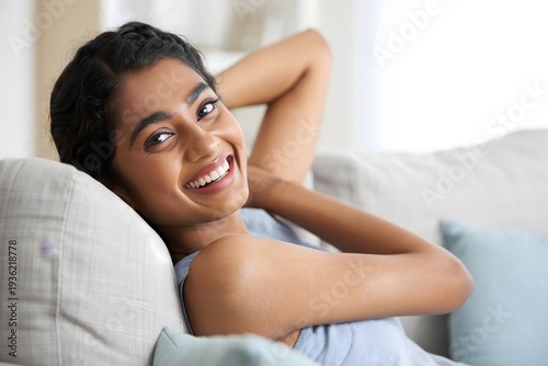 Portrait of a beautiful smiling woman relaxing on a sofa at home today