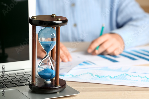 Hourglass with laptop near ...