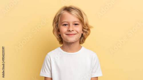 Cute blond boy in white t-shirt on yellow background with copy space