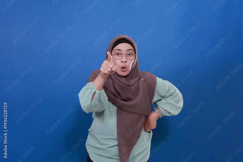 Naklejka premium An Asian Muslim woman looks frustrated because something is upsetting her. Pointing displeased and frustrated.