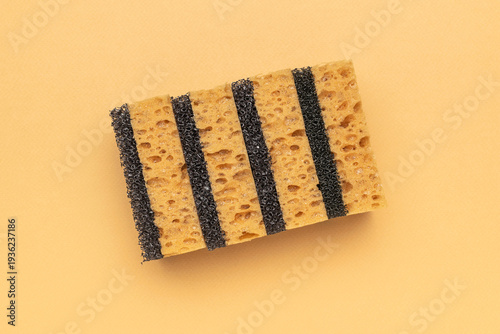 Yellow Sponge with Black Scrub Stripes on Peach Background - Minimalist Stock Photography