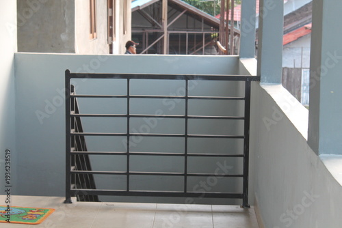 Interior shot of a minimalist black iron safety railing on a building balcony or staircase. Modern architectural detail showing home safety, construction design, and property development. Clean lines 