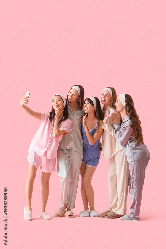 Obraz premium Group of young women in pajamas taking selfie on pink background. Hen Party