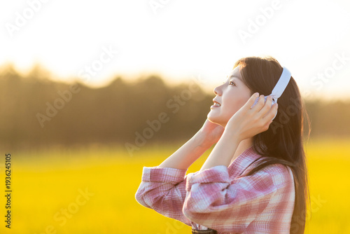 Foto A beautiful Chinese woman listening to music in golden rice paddies in autumn