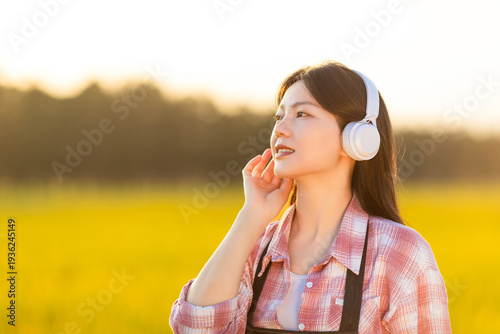Foto A beautiful Chinese woman listening to music in golden rice paddies in autumn