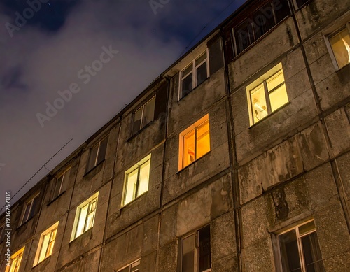 Wallpaper Mural Low-angle view of an old apartment building at night. Windows emit warm light against a dark sky. The facade shows age and texture Torontodigital.ca