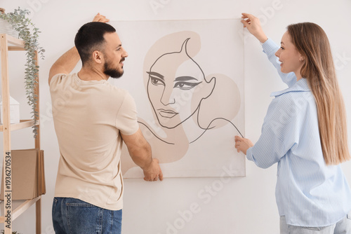 Young couple hanging painti...