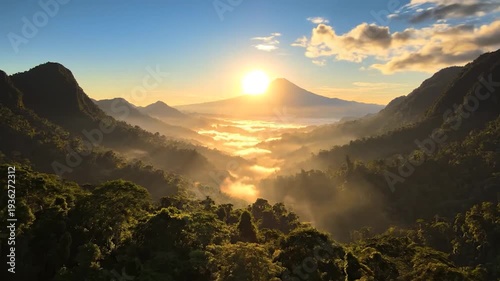 Golden sun rising over a majestic mountain range with misty valleys