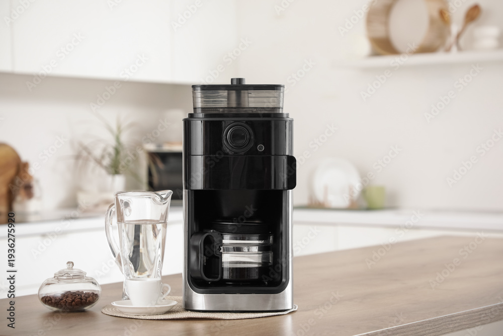 Naklejka premium Modern coffee machine and jug of water on table in kitchen, closeup