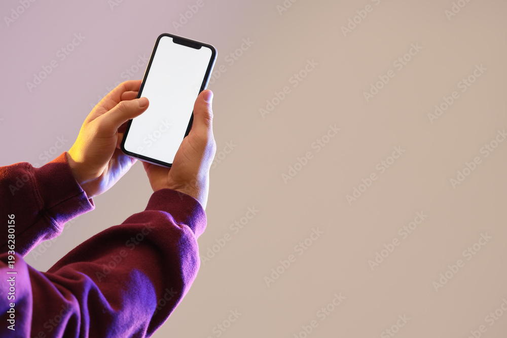 Fototapeta premium Man holding blank mobile phone on grey background
