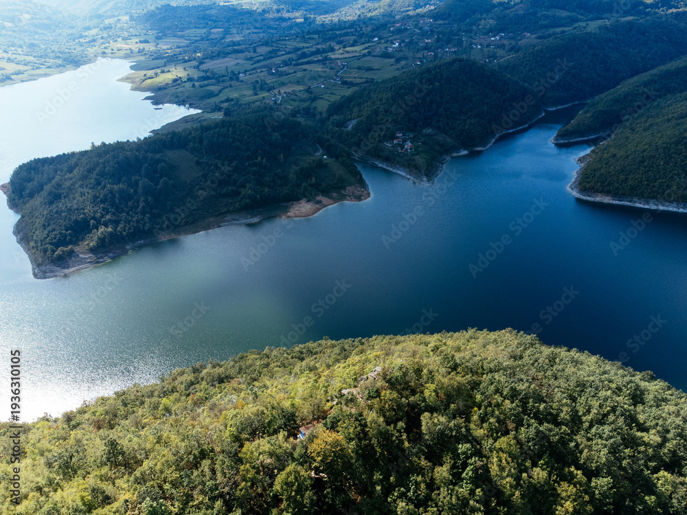 Obraz premium Aerial view of Rovni Lake reservoir and surrounding hilly landscape in Serbia. g.