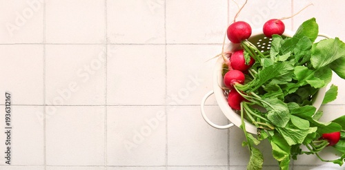 Colander of fresh radish on white tile background with space for text, top view