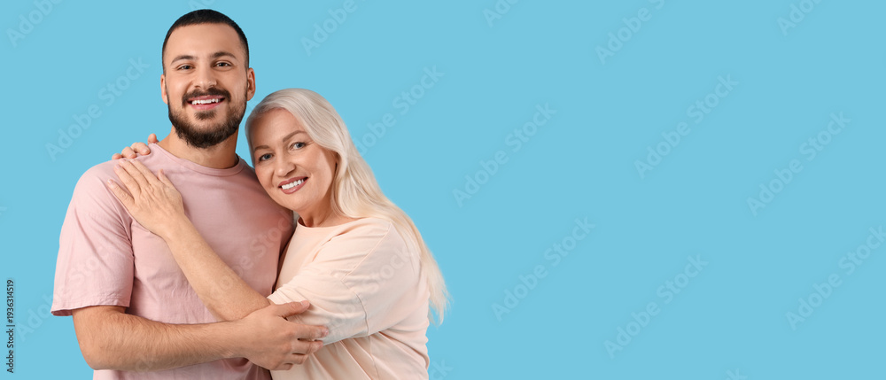 Fototapeta premium Young man hugging his mother on blue background