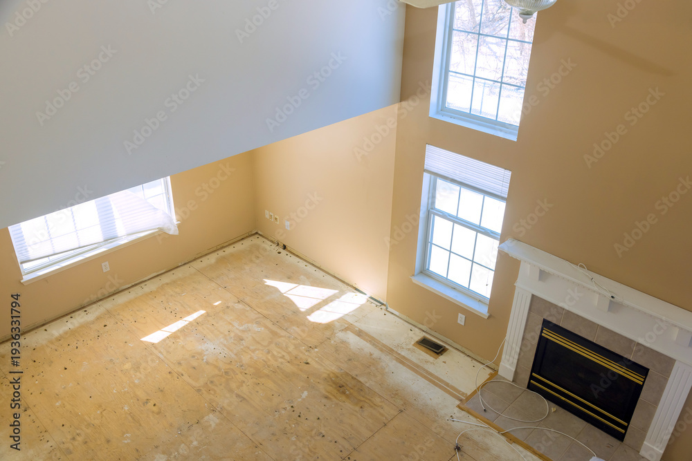 Obraz premium Sunlight enters through windows in living room where floors are bare renovation work is ongoing.