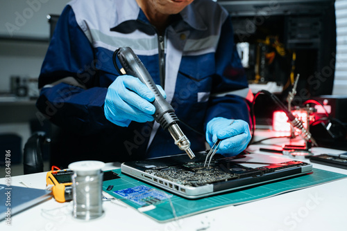 Technician performing PCB soldering and diagnostics with multimeter in electronics lab, showcasing hardware engineering