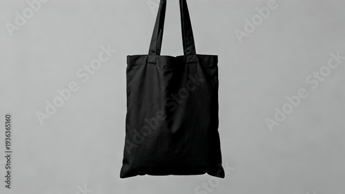 Black tote bag hanging against gray background