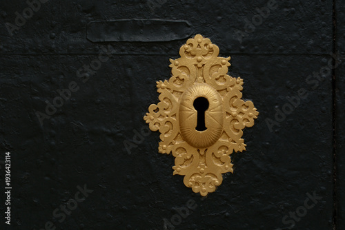 
Keyhole. An antique gold-colored lock on an old metal door.