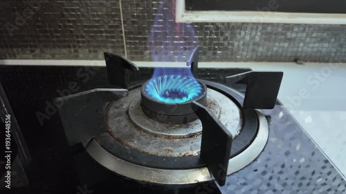 Turn on the gas stove, which has a blue flame.