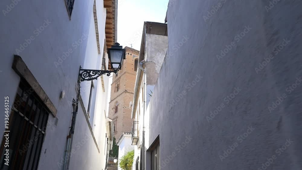 custom made wallpaper toronto digitalPOV walking shot through a narrow alley in the Albaicin district, revealing the Mudejar tower of San Bartolome Church. Bright daylight, white facades, and traditional Spanish atmosphere.