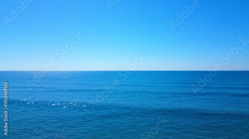 Vast blue ocean stretches peacefully under a clear azure sky with a distinct