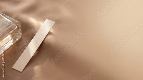 Perfume blotter beside glass bottle. Perfume test strip on warm satin background, soft sunlight for valentines day gifting, perfume branding mockup, luxury scent mood, copy space elegant