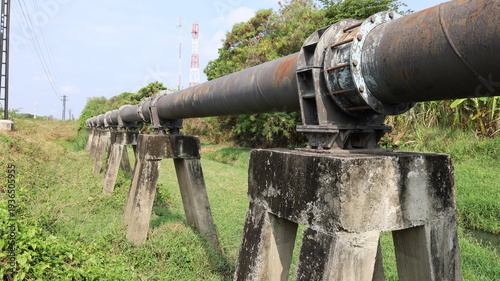 Water main pipe piers. Close-up of old concrete piers of metal plumbing pipes arranged in a straight line in a lowland urban area with copy space with selective focus.
