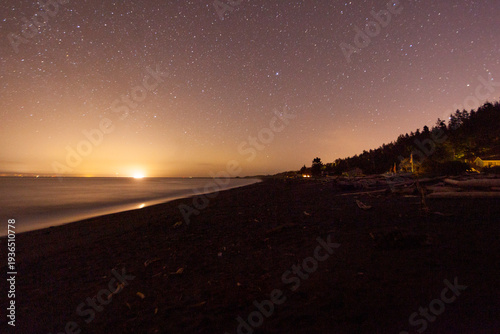Star filled sky and the sun emerging on the horizon above Freshwater Bay, Port Angeles